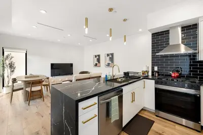 a kitchen with white cabinets and black appliances at Platinum Suite LA in Los Angeles