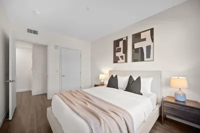 a white bedroom with a large white bed with black pillows at The Jade Hill Views - Penthouse - Pool, Gym, Balcony in Los Angeles