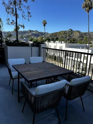 a wooden table and chairs on a patio at The Jade Hill Views - Penthouse - Pool, Gym, Balcony in Los Angeles