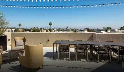 a patio with a table and chairs on a roof at The Jade Hill Views - Penthouse - Pool, Gym, Balcony in Los Angeles