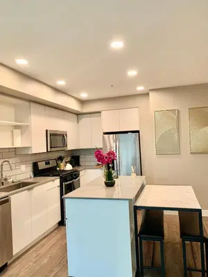 a kitchen with white cabinets and a table with flowers on it at Contemporary 2BR Prime Hollywood Location in Los Angeles