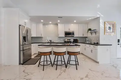 a kitchen with white cabinets and a island with bar stools at Serene Luxe Residence near Rose Bowl in Pasadena