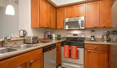a kitchen with stainless steel appliances and wooden cabinets at Marina Del Rey 2BR & 1BR Getaway - Gym - Pool - Sauna - Near Marina - Venice Beach in Los Angeles