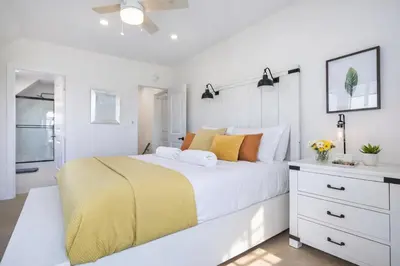 a white bedroom with a large bed and a bathroom at Modern 3BR Home Near USC, Museums & Coliseum in Los Angeles