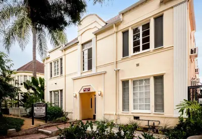 a building with a yellow door and a palm tree at Beverly Grove Hotel in Los Angeles