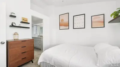 a bedroom with a white bed and a wooden dresser at Heidi House Entire Duplex Relocation Stays in Redlands