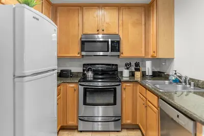 a kitchen with stainless steel appliances and wooden cabinets at Pool Hot Tub King Bed 1st Floor Condo in Corona