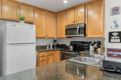 a kitchen with wooden cabinets and a white refrigerator at Pool Hot Tub King Bed 1st Floor Condo in Corona