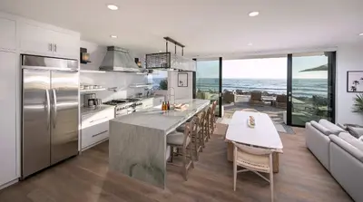 a kitchen with a table and a dining room with the ocean at Rincon Refuge - Beachfront for 6 in Ventura