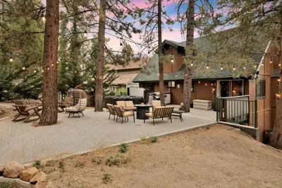 a patio with chairs and a grill in front of a house at Lakeview Pines Log Cabin #2585 in Big Bear Lake