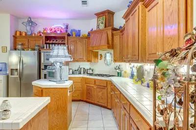 a kitchen with wooden cabinets and a refrigerator at 5 Mi to the Marketplace Roomy Bakersfield Retreat in Bakersfield