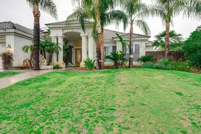 a large yard with palm trees in front of a house at 5 Mi to the Marketplace Roomy Bakersfield Retreat in Bakersfield