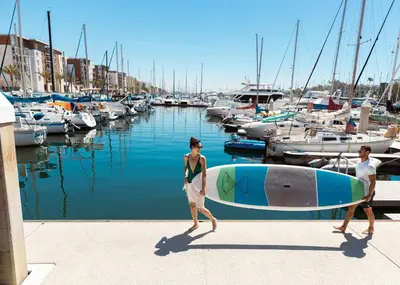 a man and woman walking by a marina with a surfboard at Sapphire Marina - Marina View Pool, Gym, Game Room in Los Angeles