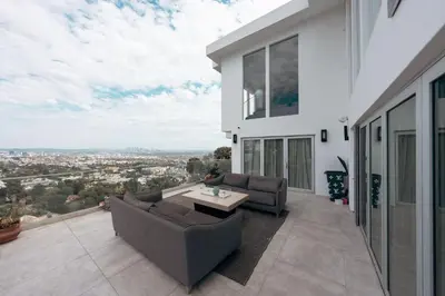 a patio with couches and a table on a balcony at Hollywood Hills Glass Cabin-Skyline view -Floor to Ceiling Windows in Los Angeles