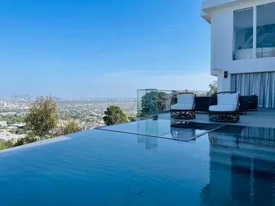 a swimming pool with two chairs on the edge of a house at Hollywood Hills Glass Cabin-Skyline view -Floor to Ceiling Windows in Los Angeles