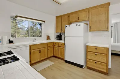 a kitchen with a white refrigerator and wooden cabinets at Round Rock Lodge at Big Bear Boulder Bay Modern Retreat w/ Pool Table Minutes to Activities in Big Bear Lake