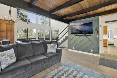 a living room with a gray couch and a large screen at Round Rock Lodge at Big Bear Boulder Bay Modern Retreat w/ Pool Table Minutes to Activities in Big Bear Lake