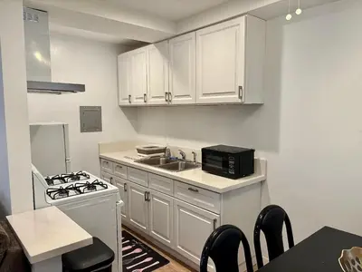 a kitchen with white cabinets and a sink and a stove at SMA Apartment in Los Angeles