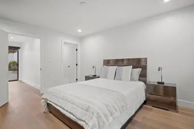 a white bedroom with a large bed with a wooden headboard at Luxury Jupiter Estate with 4BR with Pool and Jacuzzi in Los Angeles
