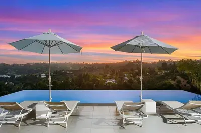 a group of chairs and umbrellas on a swimming pool at Beverly Hills Mansion W. Stunning Views in Beverly Hills