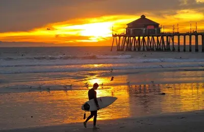 a man is walking on the beach with a surfboard at Pool House Retreat near LAX, SoFi & Beach in Inglewood