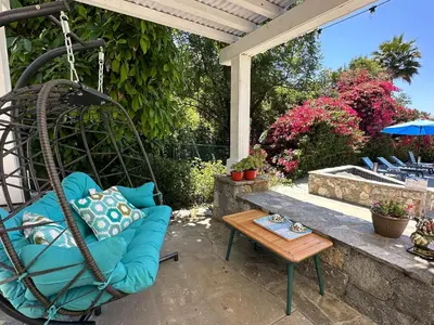 a porch with a swing and a table at Luxury LA Garden Estate Private Pool HotTub Tennis in La Habra