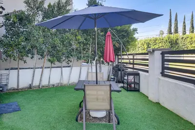 a table and a chair and an umbrella on the grass at Work and Play! North Hills Studio 15 Mi to Hollywood in North Hills