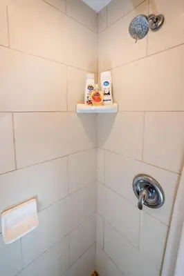 a bathroom with a white tiled shower with two shelves at Comfy Studio Near Downtown LA with AC WiFi and Snacks in Los Angeles
