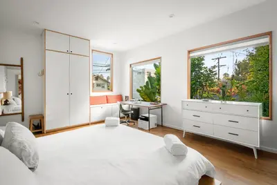 a white bedroom with a large bed and a desk at Abbot Kinney 2-Story Bungalow with Sauna and Plunge in Los Angeles