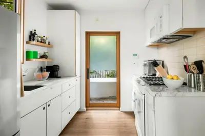 a kitchen with white cabinets and a wooden door at Abbot Kinney 2-Story Bungalow with Sauna and Plunge in Los Angeles