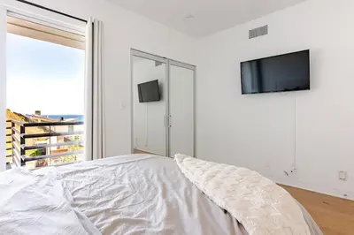 a white bedroom with a bed and a flat screen tv at Gorgeous Malibu Retreat with #Instaworthy Ocean Views in Malibu Beach