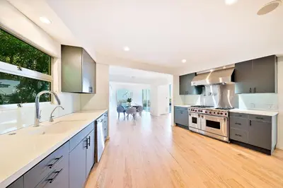 a large kitchen with white counters and a wooden floor at Stunning Modern Estate in BH with Pool, Spa, and Views in Los Angeles