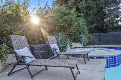 two chairs and a table next to a pool at Corporate & Family Retreat Seven Oaks Pool Home in Bakersfield