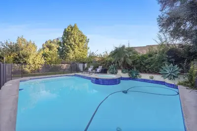 a large swimming pool with blue tiles on a patio at Corporate & Family Retreat Seven Oaks Pool Home in Bakersfield