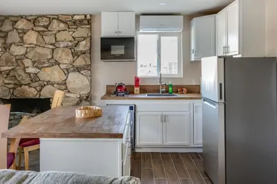 a kitchen with white cabinets and a stone wall at Cozy 1BR Guest House with Mountain View in Simi Valley in Simi Valley