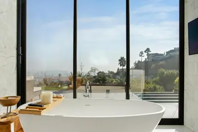 a large white bath tub in a room with large windows at Belfast Estate in Los Angeles