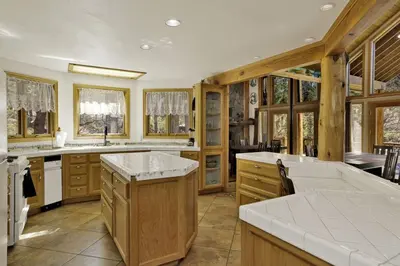 a large kitchen with wooden cabinets and white counter tops at The Village Timber Lodge at Big Bear - Downtown Log Cabin Retreat in Big Bear Lake