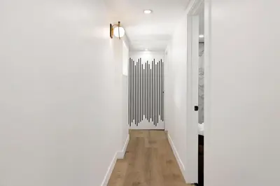a hallway with white walls and wooden floors and a white door at Vista Pines at Big Bear Lake– Your Ultimate Mountain Escape in Big Bear Lake