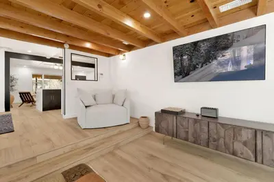 a living room with a white chair and a tv at Vista Pines at Big Bear Lake– Your Ultimate Mountain Escape in Big Bear Lake