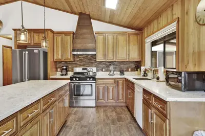 a kitchen with wooden cabinets and stainless steel appliances at Pines & Needles Mountain Retreat by Big Bear Vacations in Big Bear Lake