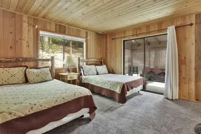 a bedroom with two beds and a sliding glass door at Pines & Needles Mountain Retreat by Big Bear Vacations in Big Bear Lake