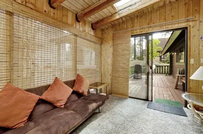 a living room with a brown couch and a patio at Pines & Needles Mountain Retreat by Big Bear Vacations in Big Bear Lake