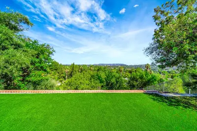 a large green lawn with trees and a blue sky at Incredible View, Huge Pool & Basketball! in Tarzana