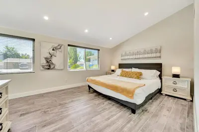 a bedroom with a large bed and two windows at Incredible View, Huge Pool & Basketball! in Tarzana