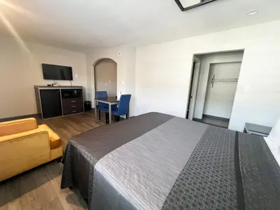a bedroom with a bed and a table and a tv at Cloud 9 Inn - El Ciello Inn in Pico Rivera