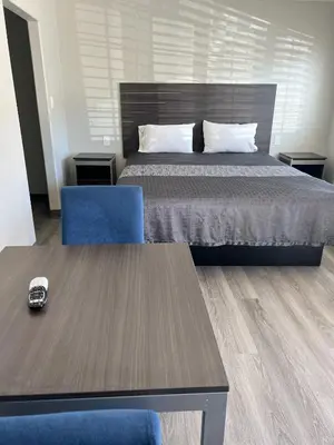 a bedroom with a bed and a blue chair and a table at Cloud 9 Inn - El Ciello Inn in Pico Rivera