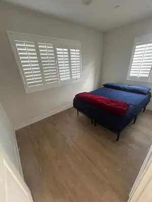 a bedroom with a bed with blue sheets and two windows at Santa Ana Vibes in Santa Ana