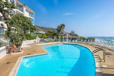 a swimming pool with chairs and the ocean in the background at Aquareve in Malibu Beach