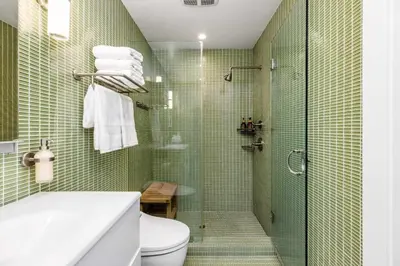 a green tiled bathroom with a shower and a toilet at Aquareve in Malibu Beach