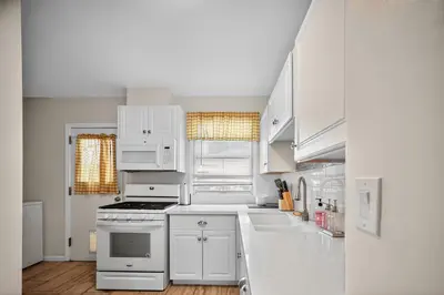 a white kitchen with white cabinets and appliances at Cozy Modern 2BR 1BA near LAX, LMU, SoFi Stadium and the Beach in Los Angeles